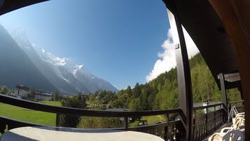 Weitläufige Aussicht vom Balkon mit Blick auf Berge, darunter schneebedeckte Gipfel und einen bewaldeten Bereich.