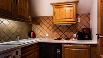 A kitchen with wooden cabinets, a Bosch dishwasher, a coffee maker, and a kettle.