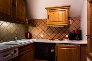 A kitchen with wooden cabinets, a Bosch dishwasher, a coffee maker, and a kettle.