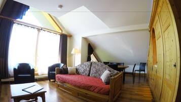 Una habitación acogedora con un sofá de madera, una mesita y un escritorio con sillas.