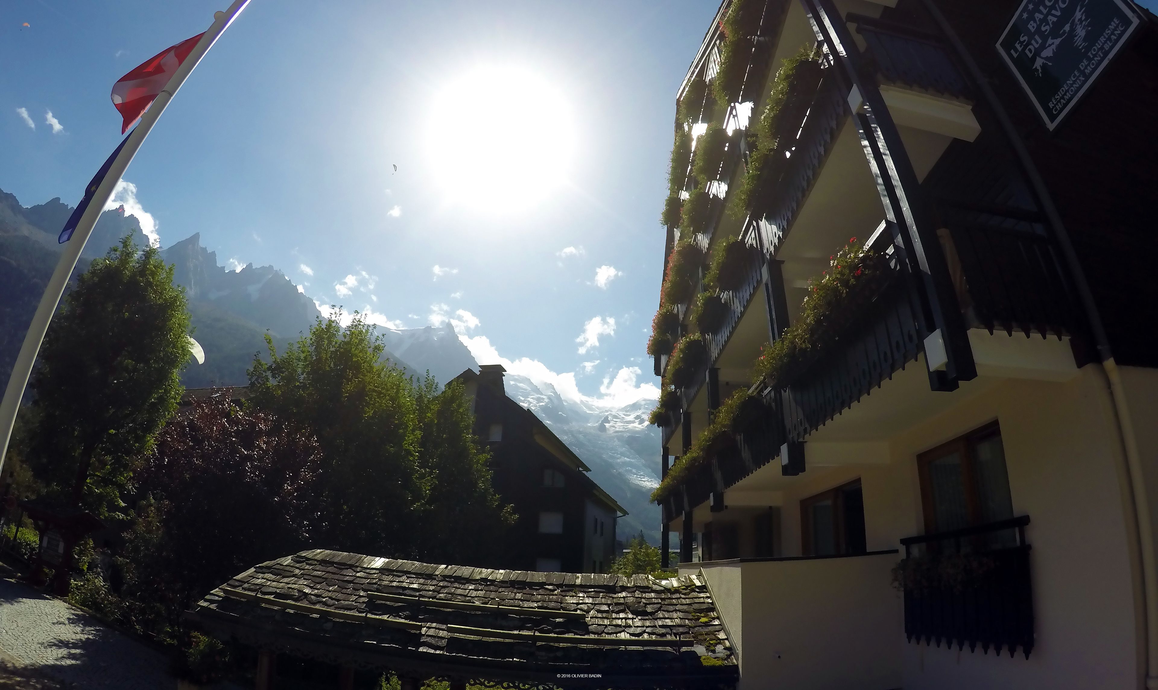Ein traditionelles Chalet mit Steinziegeldach, einer Flagge und einem Berg im Hintergrund.