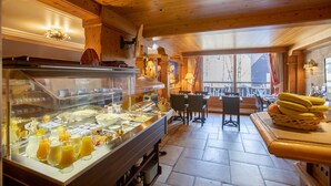 Espaço de buffet com variedade de alimentos e bebidas, decoração em madeira e vista para o exterior.