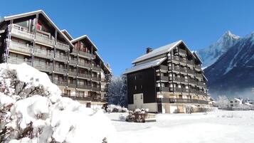 A snow-covered building with multiple balconies and a mountain backdrop.