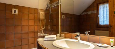 Un baño con un lavamanos blanco, un espejo grande y una ducha.