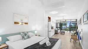 Una habitación de hotel moderna con una cama grande, un escritorio, una silla y un balcón con vistas.
