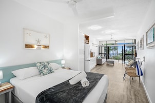Una habitación de hotel moderna con una cama grande, un escritorio, una silla y un balcón con vistas.