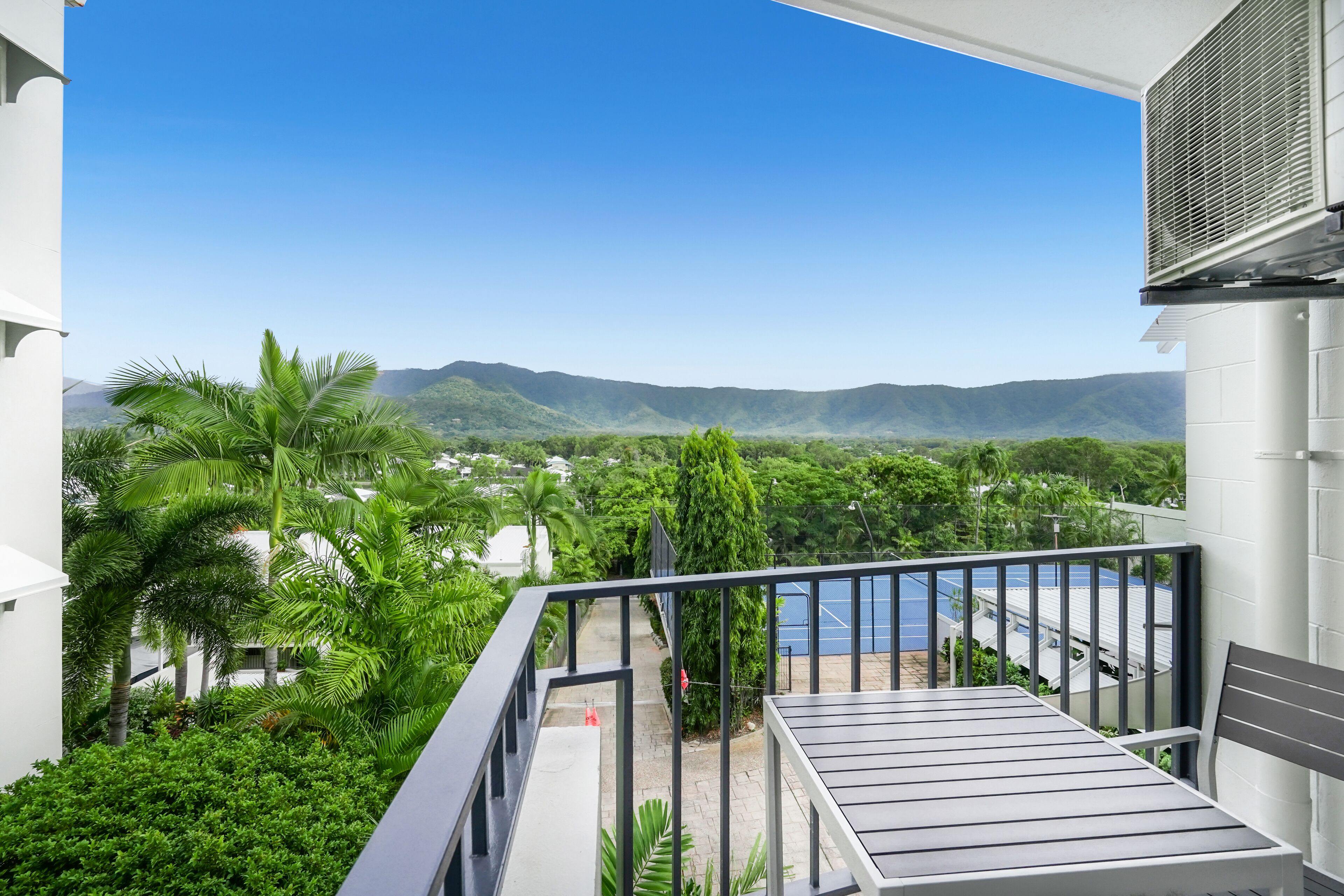 Un balcon offrant une vue sur un paysage montagneux, une piscine et une végétation luxuriante.