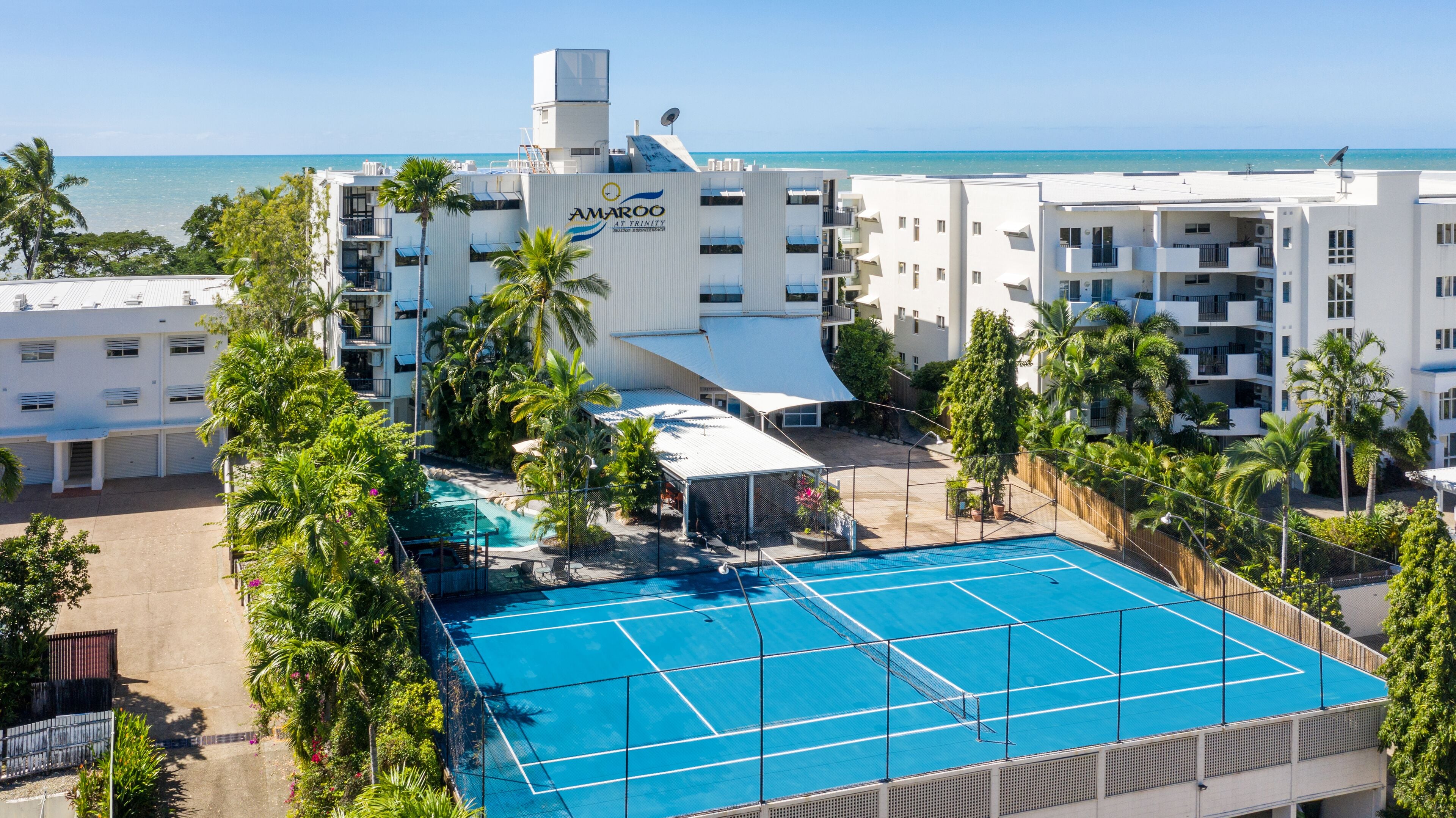 Un hotel amb piscina, envoltat de palmeres i vistes a l'oceà.