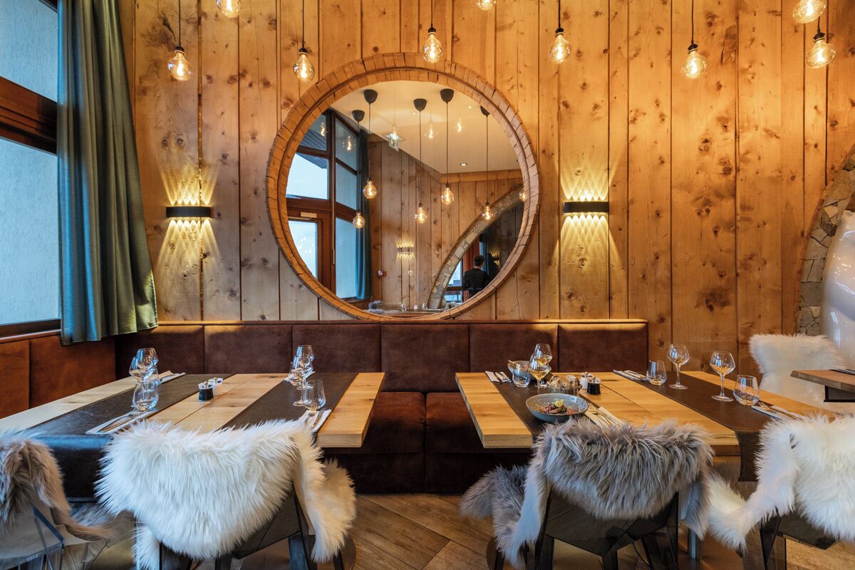 Un restaurant aux murs en bois, doté d’un grand miroir et d’une table en bois dressée pour le repas.