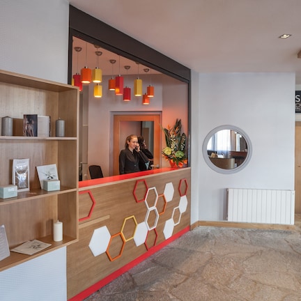 A reception area with a wooden reception desk, a wall-mounted display of spa-related items, and a circular mirror on the wall.