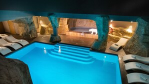 A pool area with a clear blue water feature, surrounded by rock formations and lounge chairs.