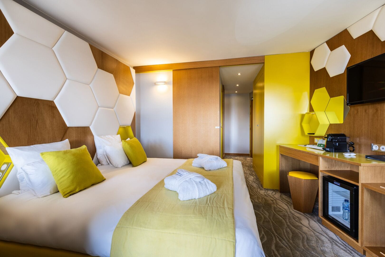 Une chambre d’hôtel avec un grand lit, un bureau avec un ordinateur et une télévision.