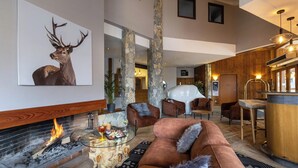 A modern living room with a fireplace, a large deer painting, and a cozy seating area.