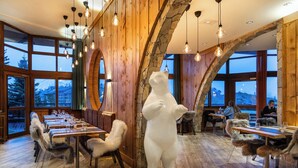 A restaurant with wooden walls, a polar bear statue, and tables set for dining.