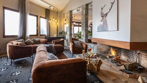 A modern living room with a fireplace, leather sofas, and a large window.