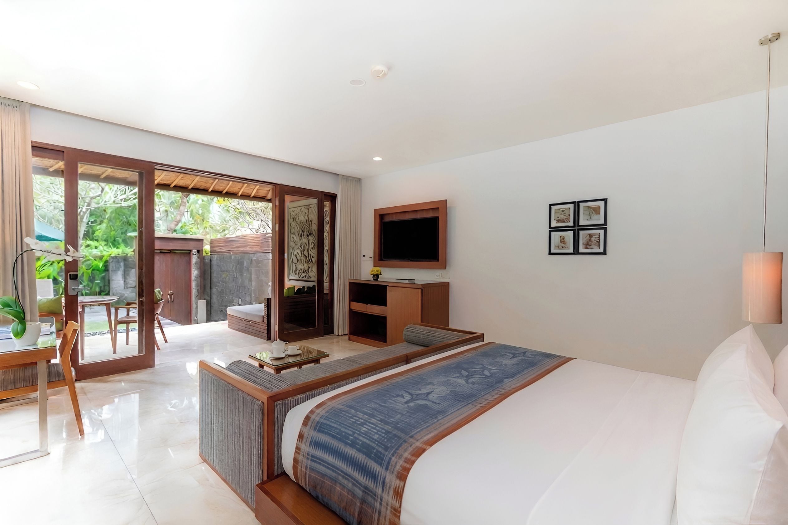 Un dormitorio moderno con una cama grande, un televisor y un comedor con vistas al jardín.