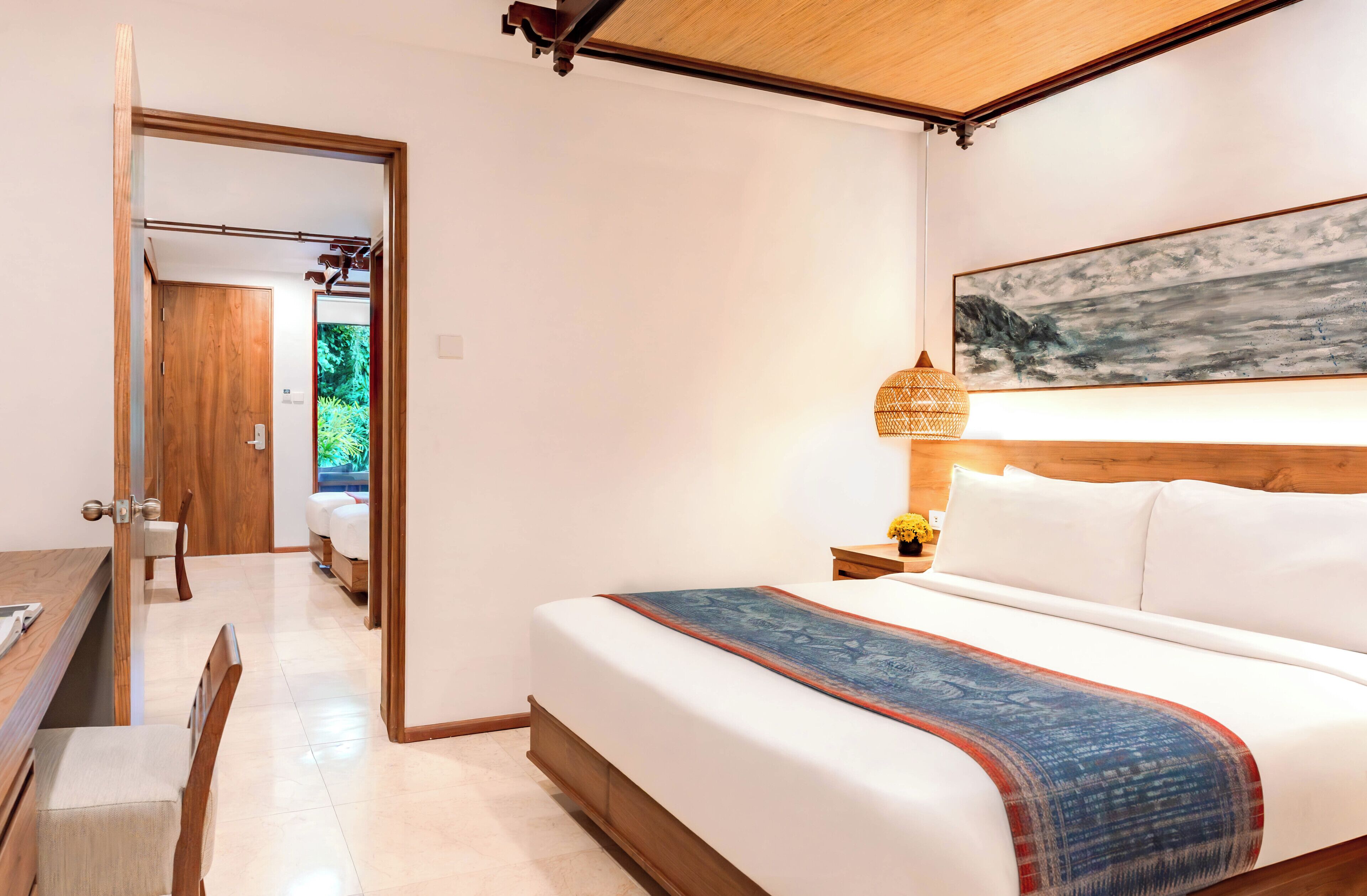 Un dormitorio con cama, mesita de noche, lámpara y un cuadro en la pared.