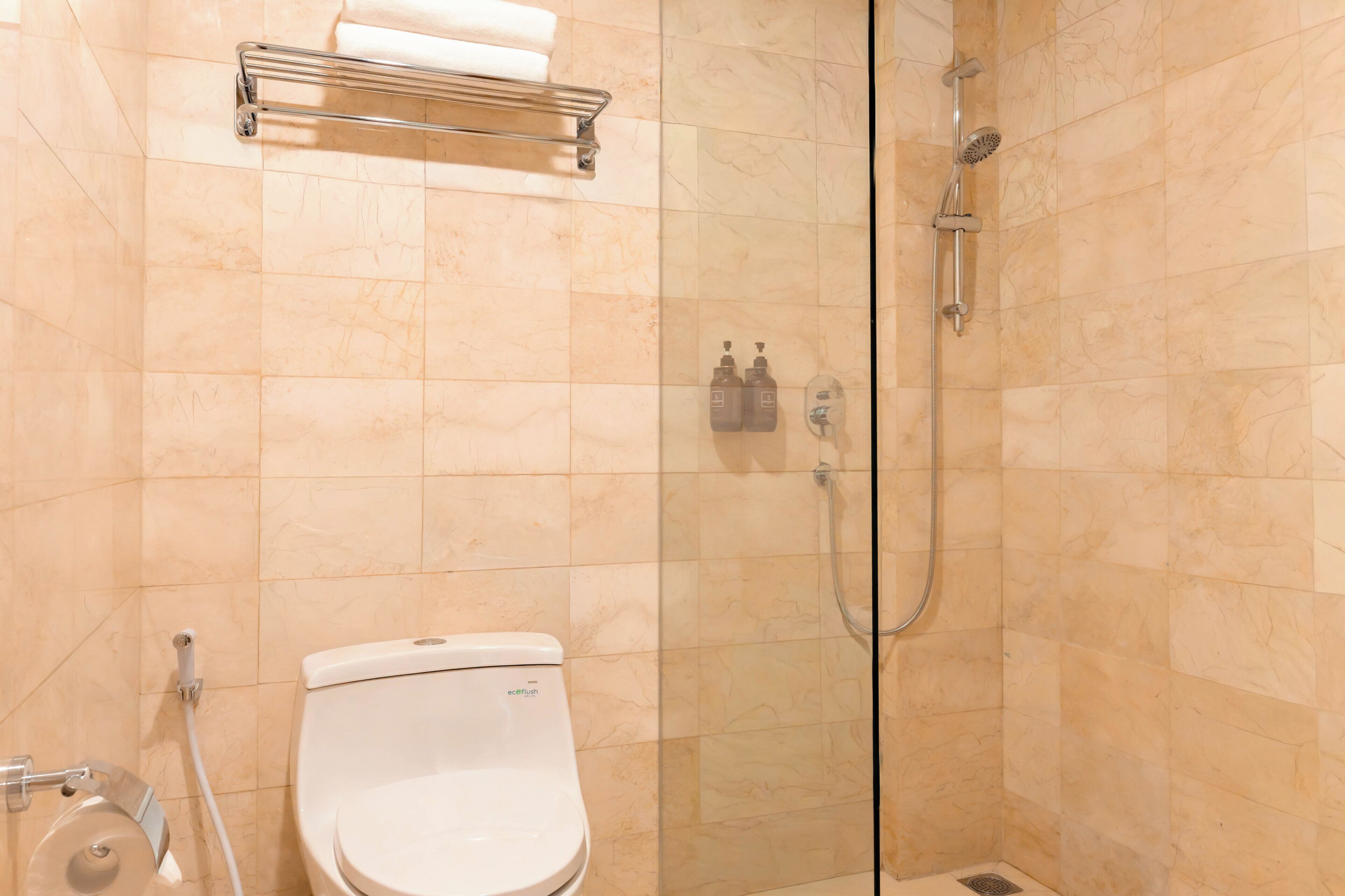 A bathroom with a toilet, a glass-enclosed shower, and a towel rack.