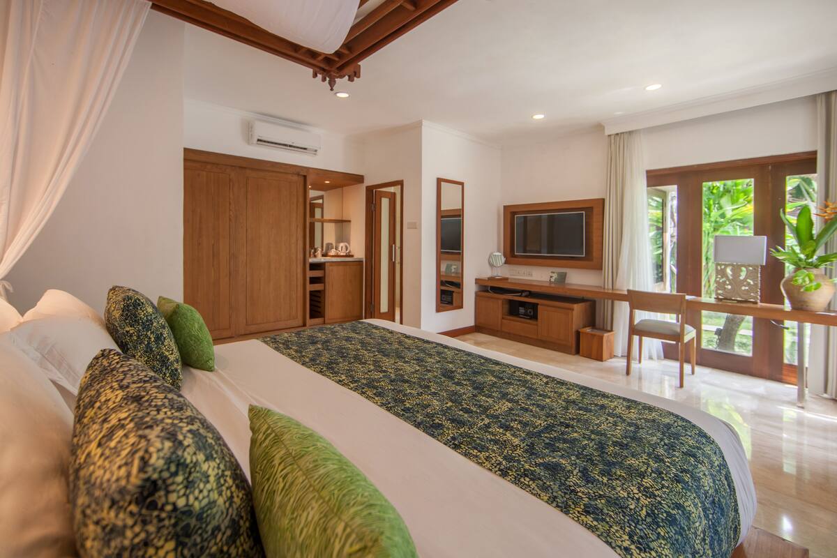 A bedroom with a large bed, a desk, a chair, and a television.
