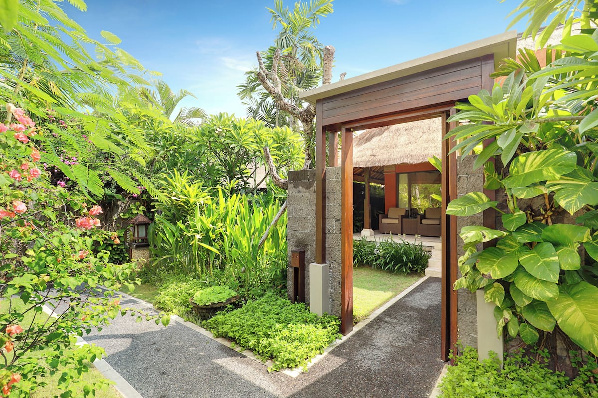 A modern house with a thatched roof, surrounded by lush greenery and a well-maintained garden.