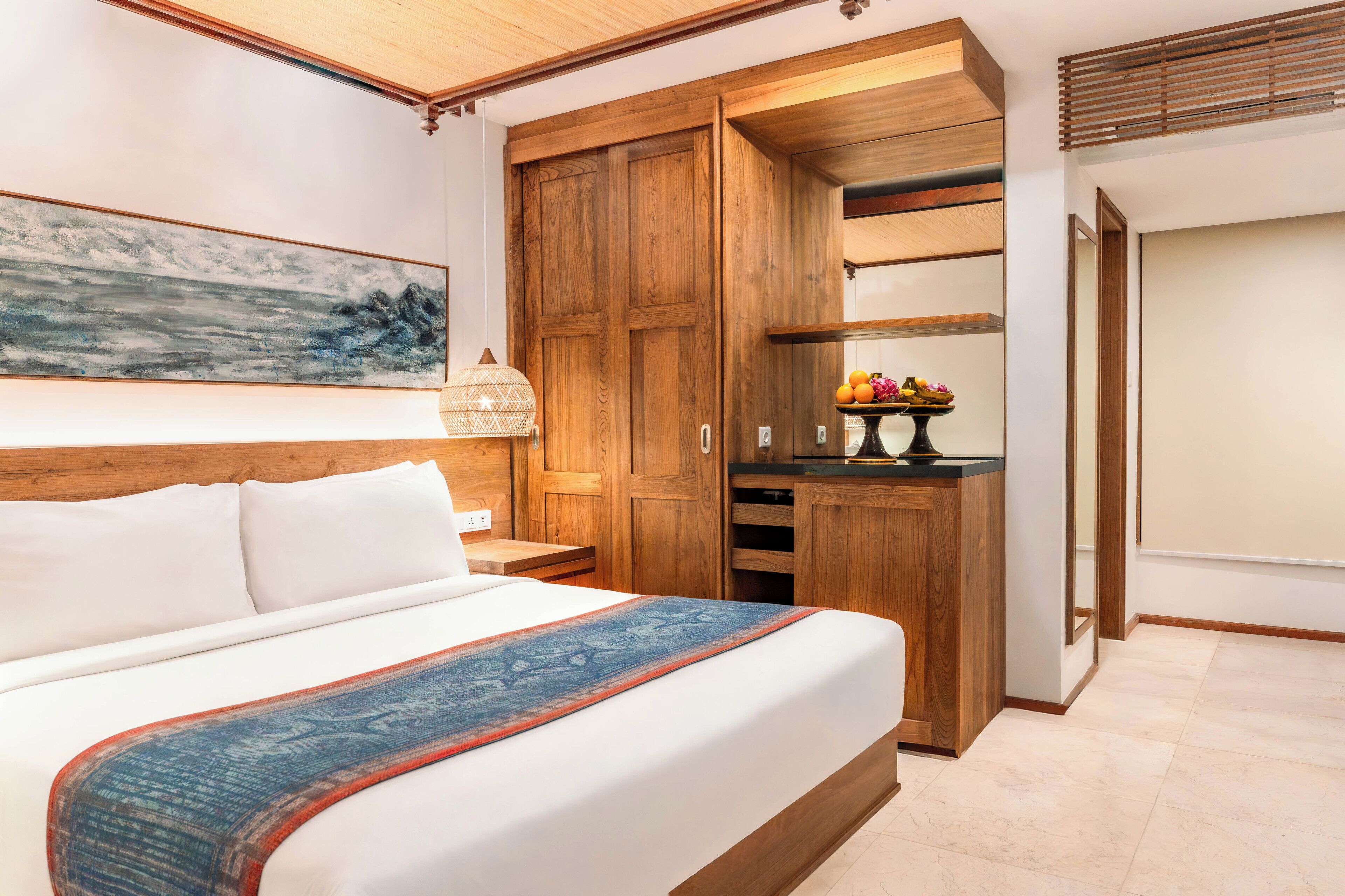 A bedroom with a large bed, wooden wardrobe, and a painting on the wall.