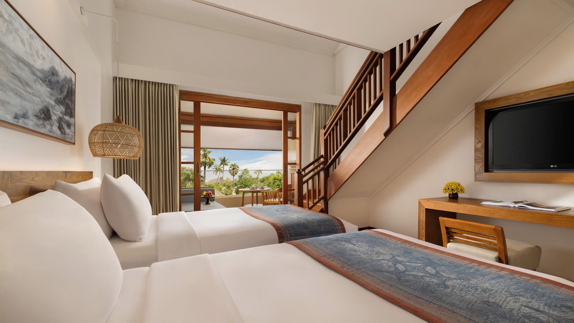 A hotel room with a bed, a desk, a TV, and a staircase.