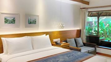 A hotel room with a large bed, a bedside table, a chair, and a window with a view of greenery.