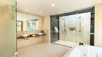 Un baño moderno con ducha de vidrio, dos lavamanos y una bañera grande.