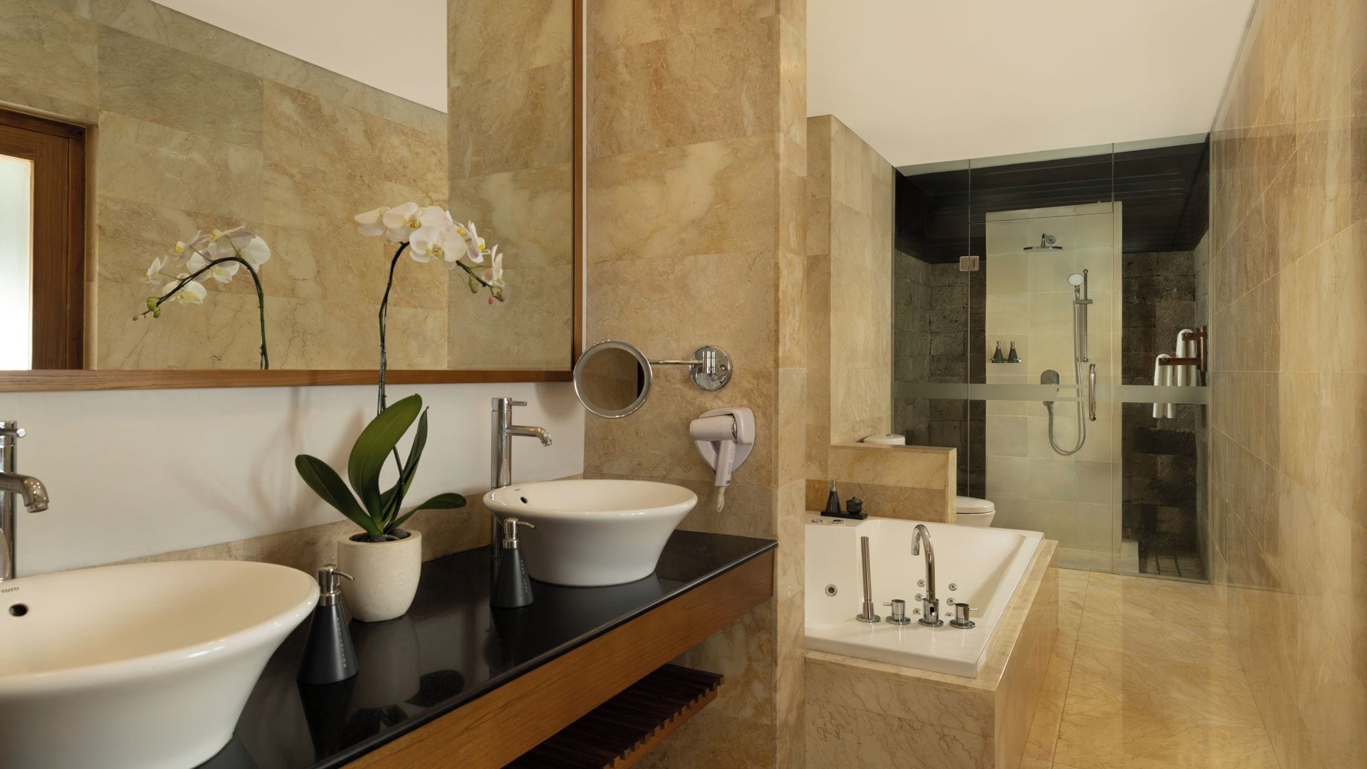 Un baño moderno con dos lavamanos, un espejo, una planta y una zona de ducha.