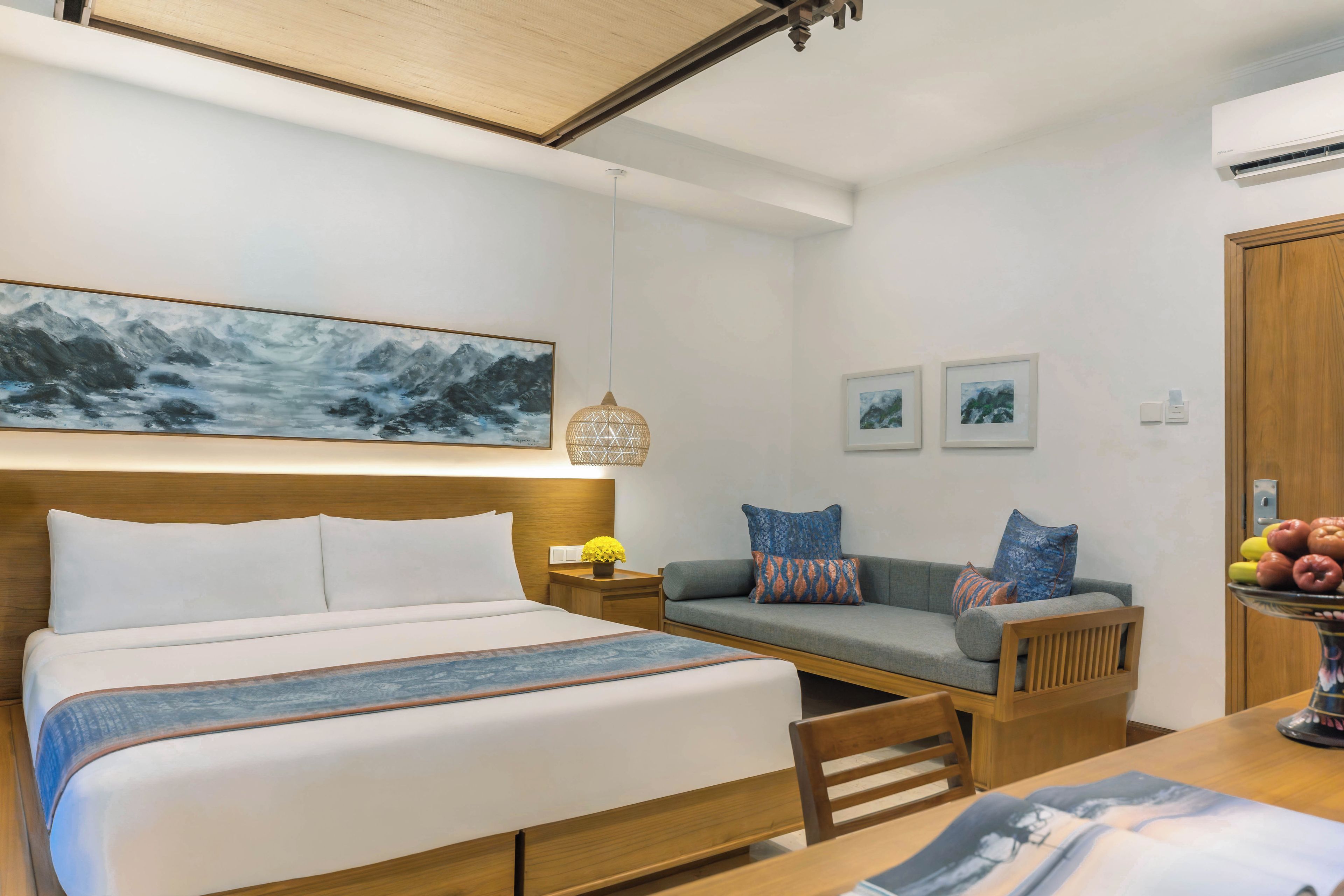 Habitación de hotel con cama, sofá, mesa de comedor y aire acondicionado instalado en la pared.