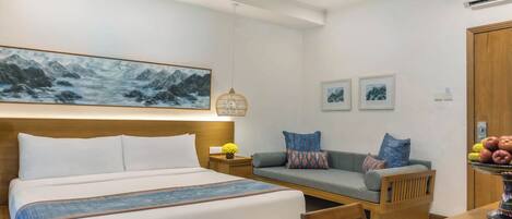 Habitación de hotel con cama, sofá, mesa de comedor y aire acondicionado instalado en la pared.