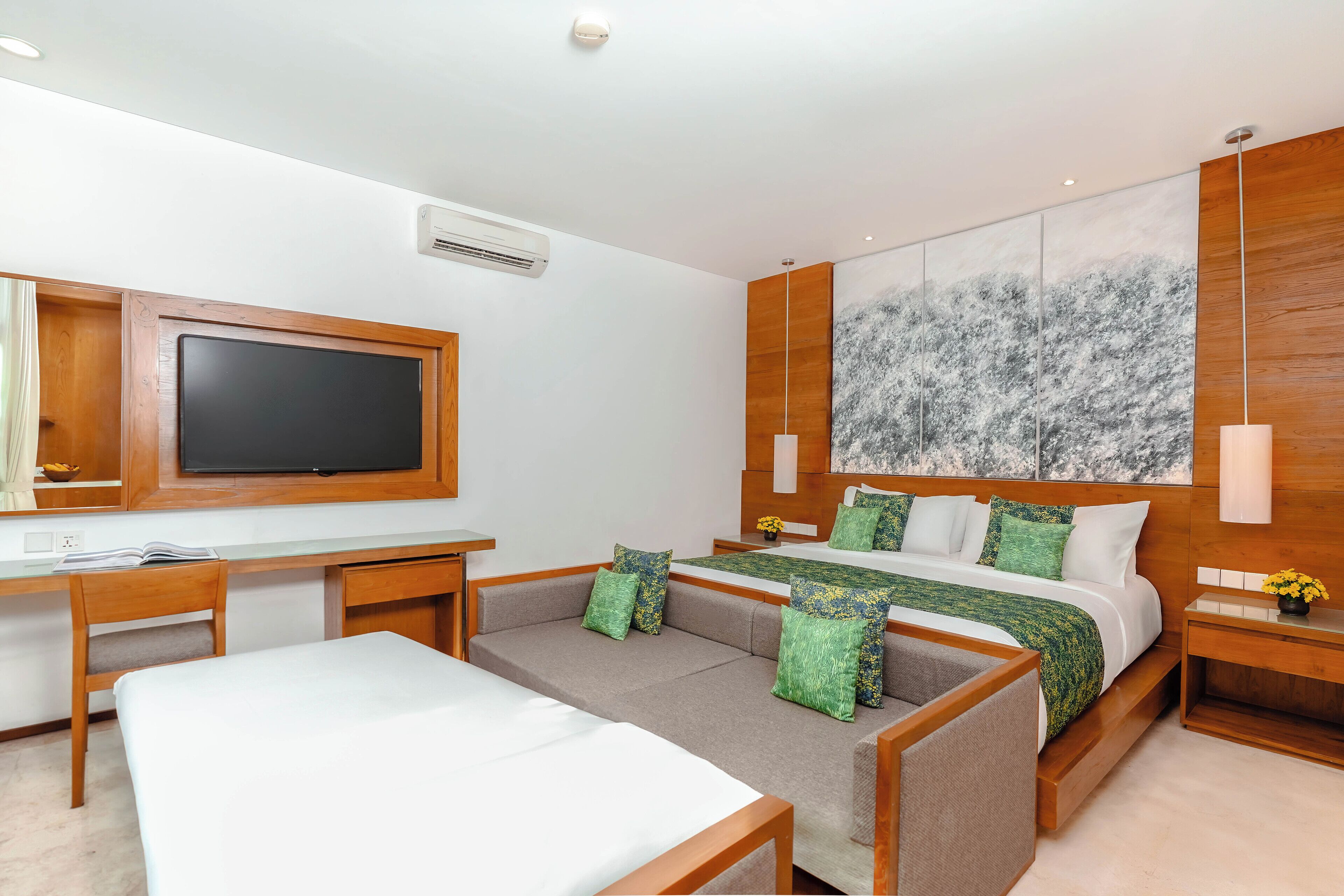 A modern hotel room with a large bed, a desk, and a sofa.