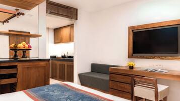 Una habitación moderna con cama, escritorio, televisor y kitchenette.