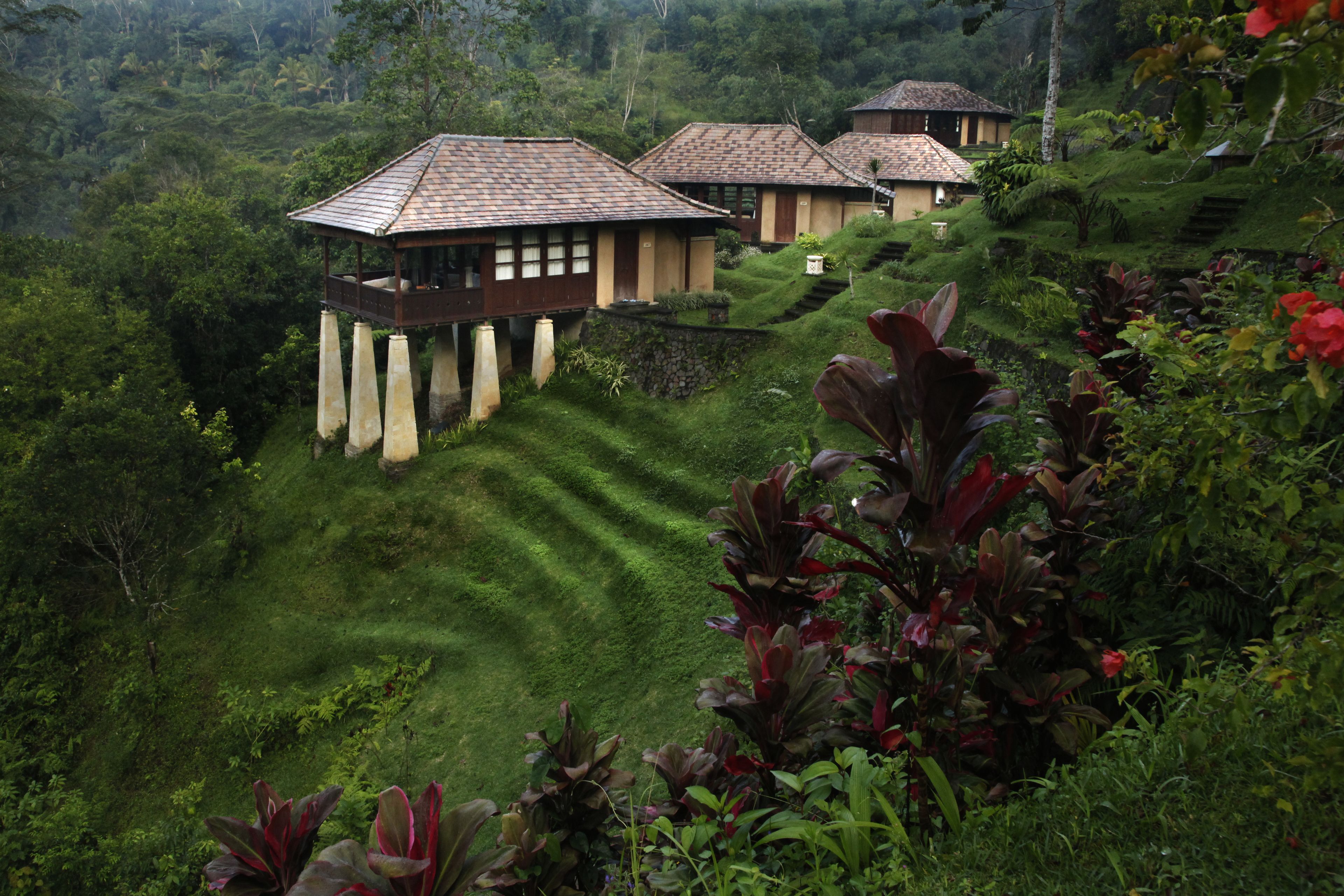 Vue sur un complexe hôtelier situé sur une colline, composé de plusieurs bâtiments de style bungalow, chacun doté d’un balcon et d’un toit en tuiles.
