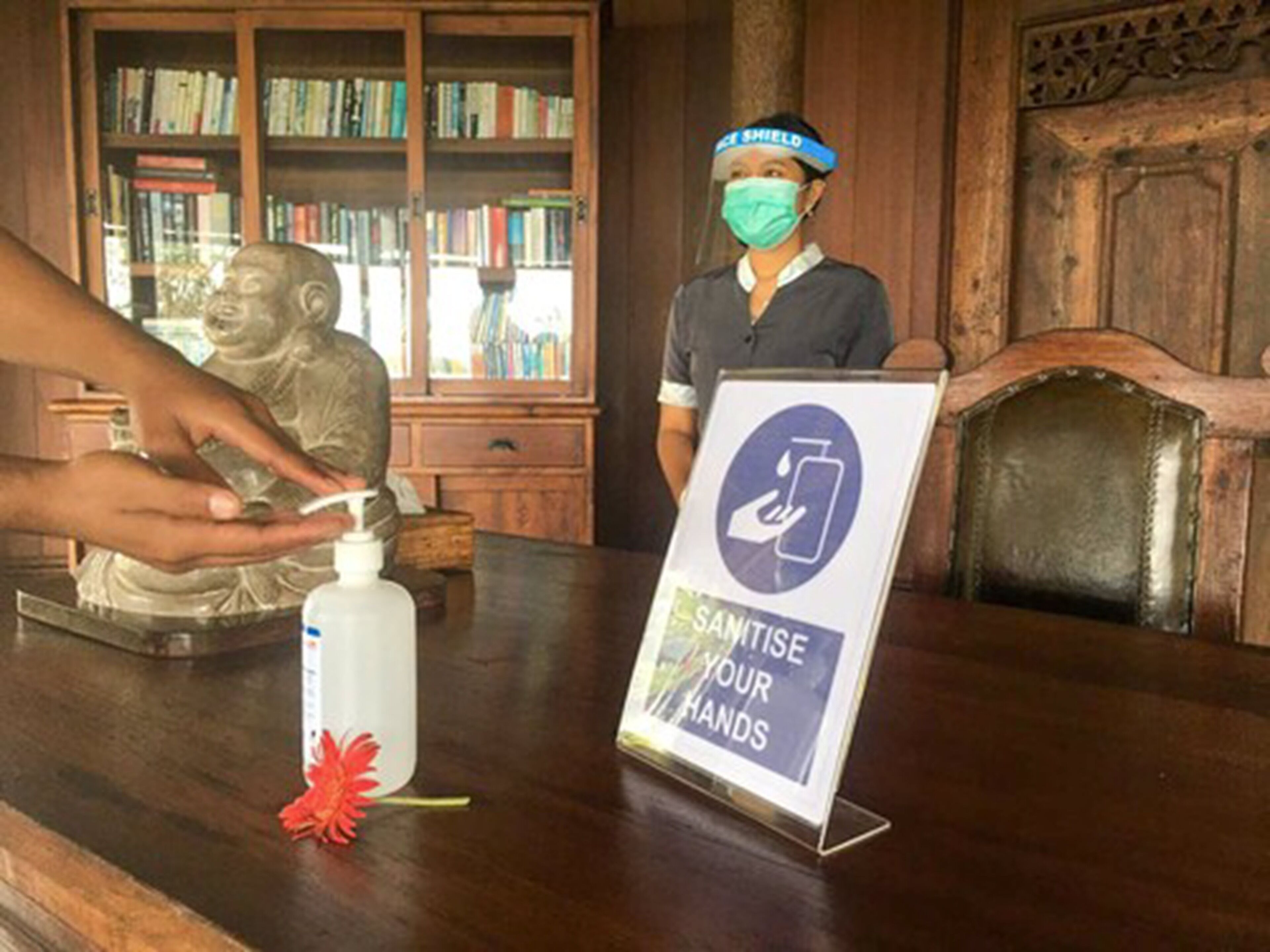 Una persona desinfectando sus manos en un mostrador con un cartel que dice 