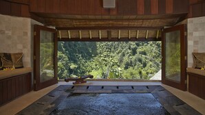 Una habitación con un ventanal grande, un banco de madera y suelo de piedra.