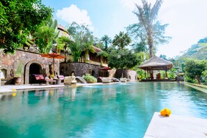 A pool area with lounge chairs and a thatched-roof gazebo. - Bagus Jati Health & Well Being Retreat (Tegallalang)