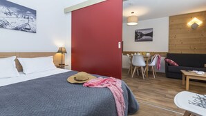 Una habitación de hotel con una cama, un escritorio, una silla, un sofá y una mesa de comedor.