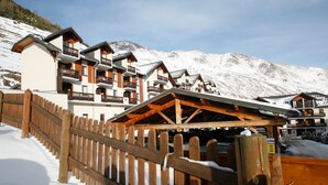 Un hotel de varios pisos con balcones, barandillas de madera y una montaña nevada al fondo.