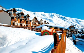 A snow-covered mountain resort with wooden buildings, a wooden fence, and a snow-covered ground. - Résidence Odalys L' Ouillon (Saint-Sorlin-d'Arves)
