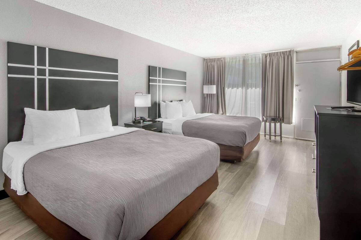 A hotel room with two beds, a desk, a TV, and a wardrobe.
