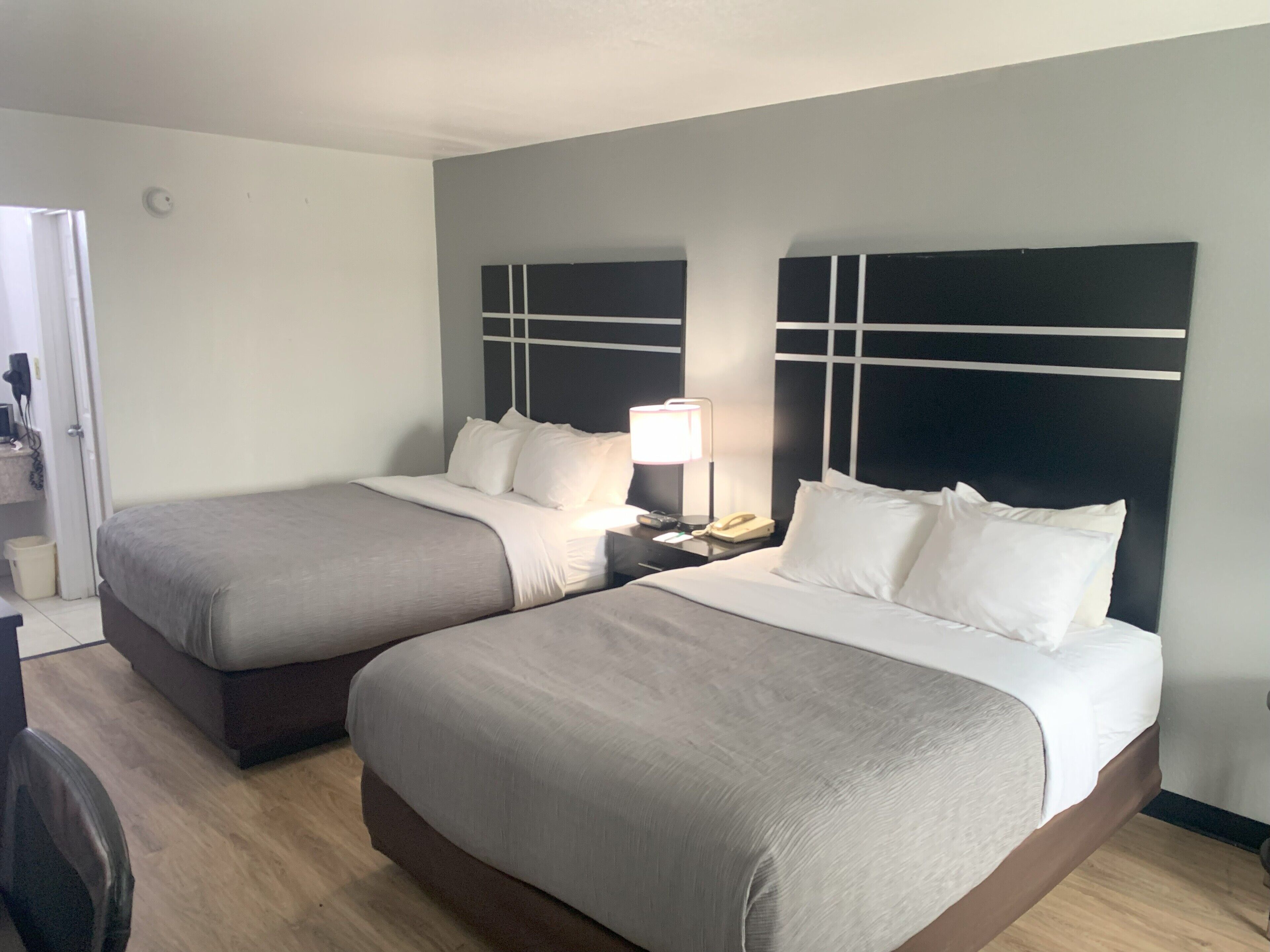 A hotel room with two beds, a bedside table with a lamp, and a telephone.