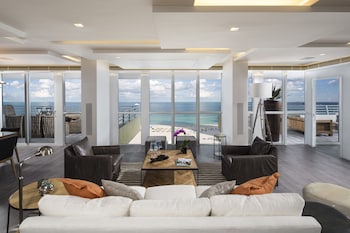 A room with a large window overlooking a beach and a rocky outcrop. at Hilton Bentley Miami/South Beach