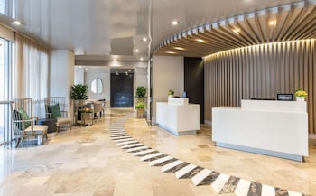 A modern restaurant with a bar area, wooden flooring, and large windows offering a view of the outdoors. at Hilton Bentley Miami/South Beach