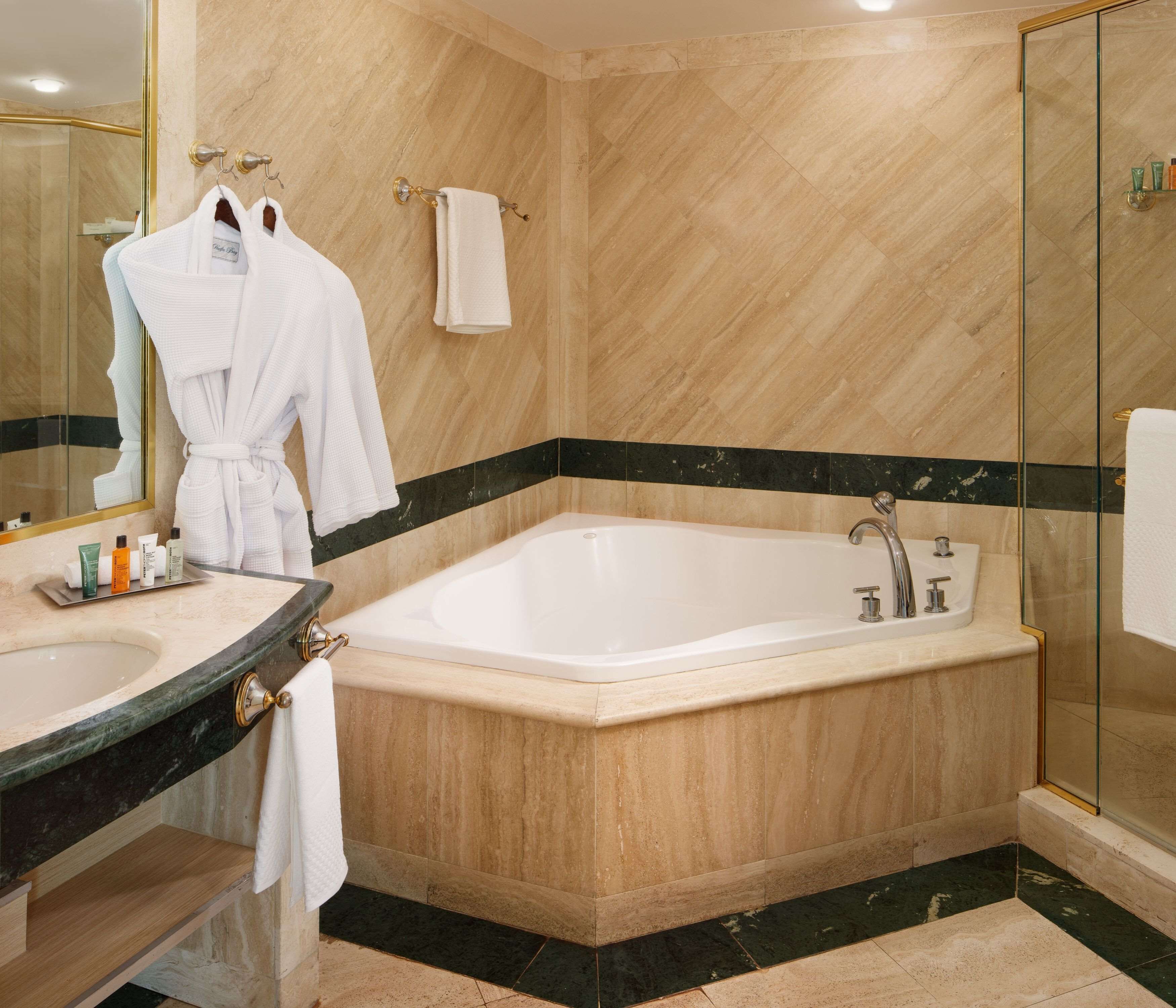 Une salle de bain moderne avec une baignoire sur pieds, une douche à parois de verre et un meuble-lavabo avec des articles de toilette.