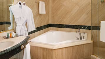 Une salle de bain moderne avec une baignoire sur pieds, une douche à parois de verre et un meuble-lavabo avec des articles de toilette.