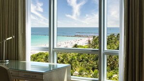 A room with a large window overlooking a beach and a rocky outcrop. - Hilton Bentley Miami/South Beach (Miami Beach)