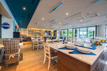 A modern restaurant with white furniture, a bar area, and a mural of a cityscape. at Hilton Bentley Miami/South Beach