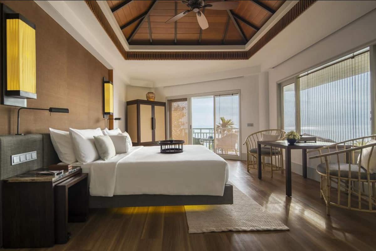 A bedroom with a bed, bedside table, and a view of the outdoors.