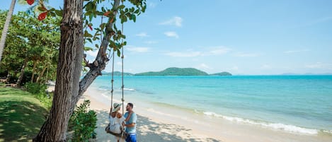 Een privéstrand, wit zand, ligstoelen aan het strand, parasols